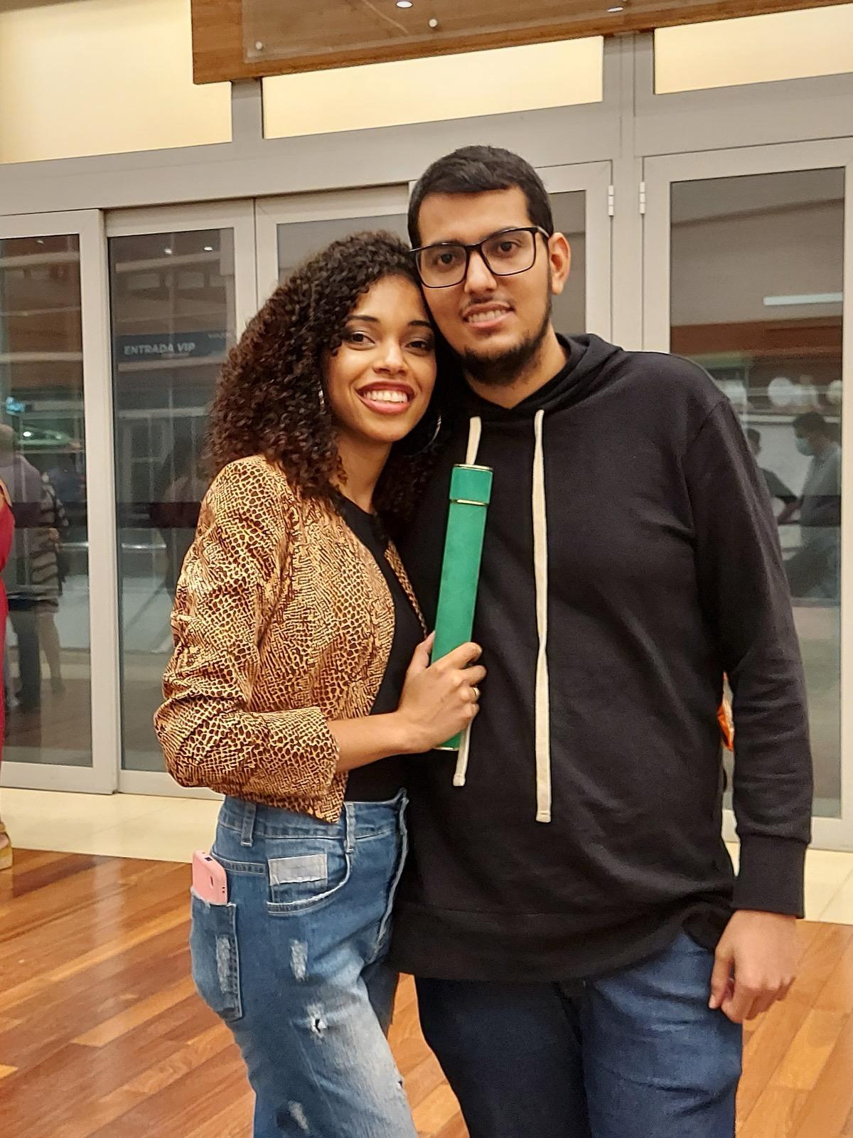 Foto do casal abraçado segurando diploma